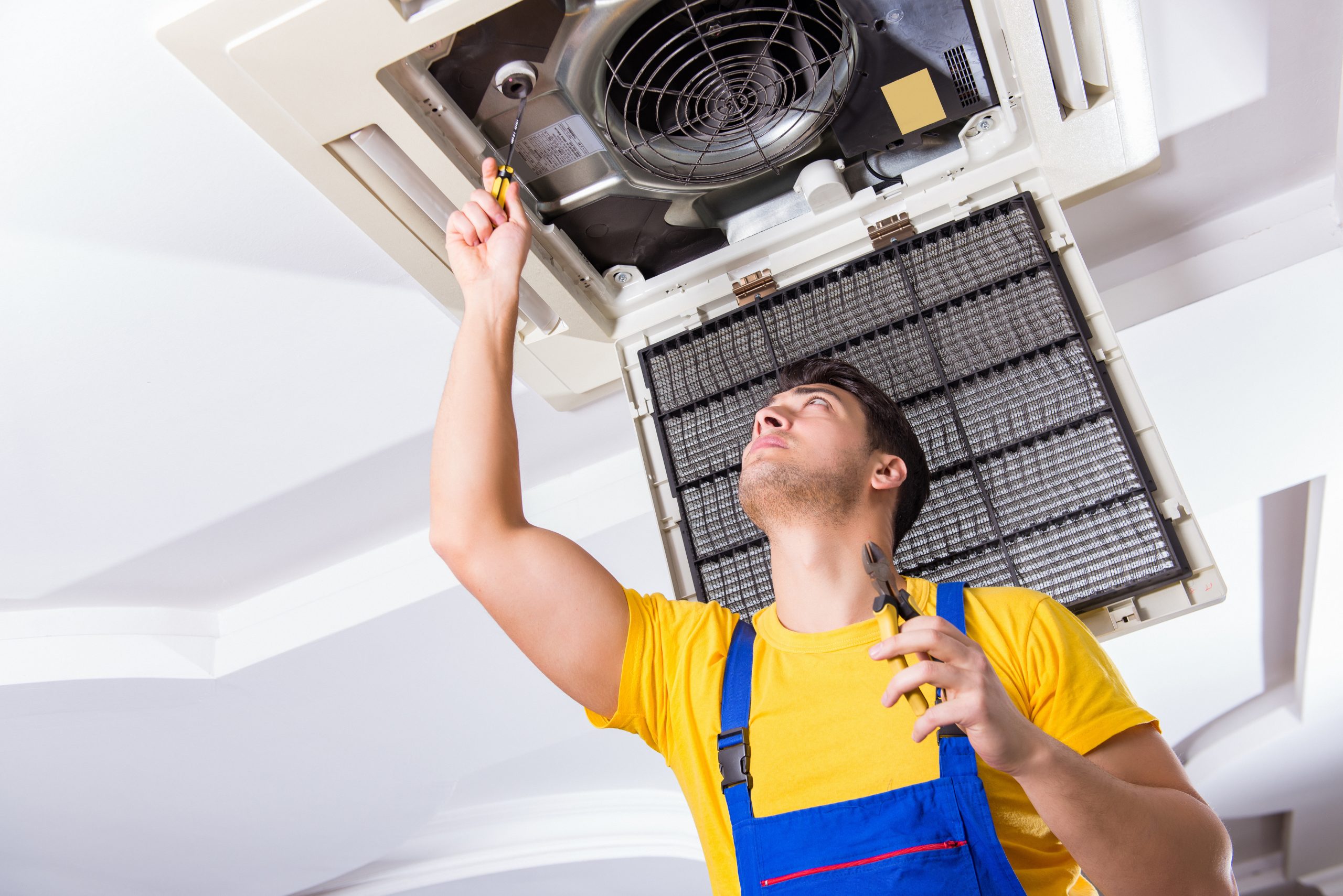 Repairman repairing ceiling air conditioning unit